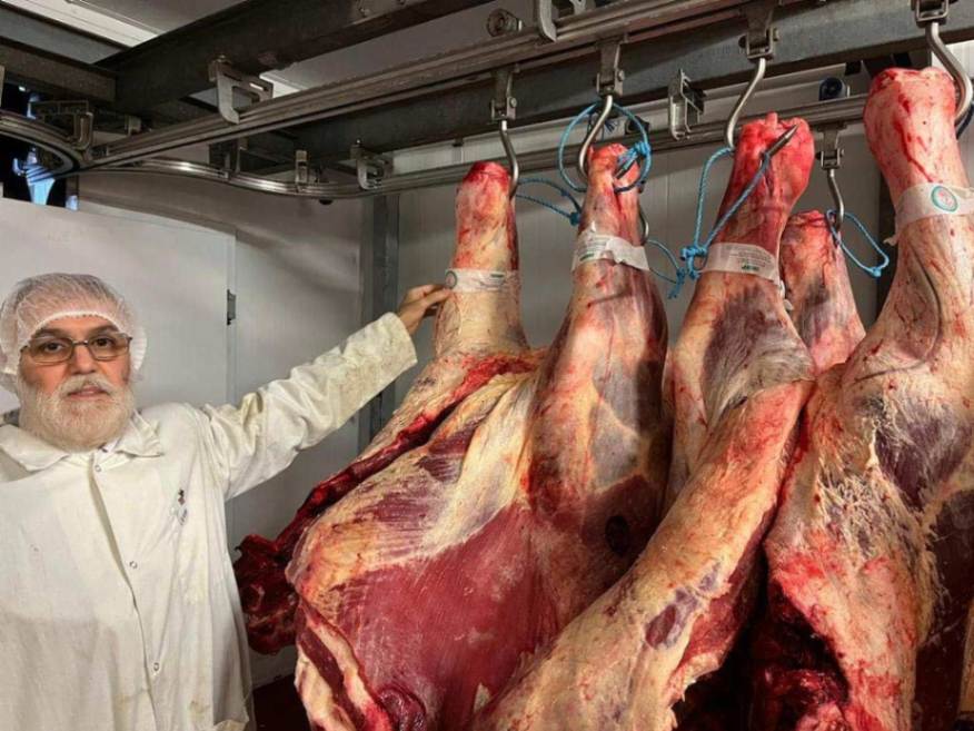 un inspecteur de viande avec des carcasses de boeuf suspendus